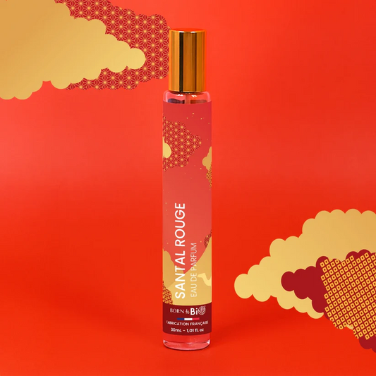 Eau de Parfum Santal Rouge Born to Bio sur un fond rouge avec des motifs orientaux dorés. Pyramide olfactive audacieuse : Santal, Jasmin et Mandarine.