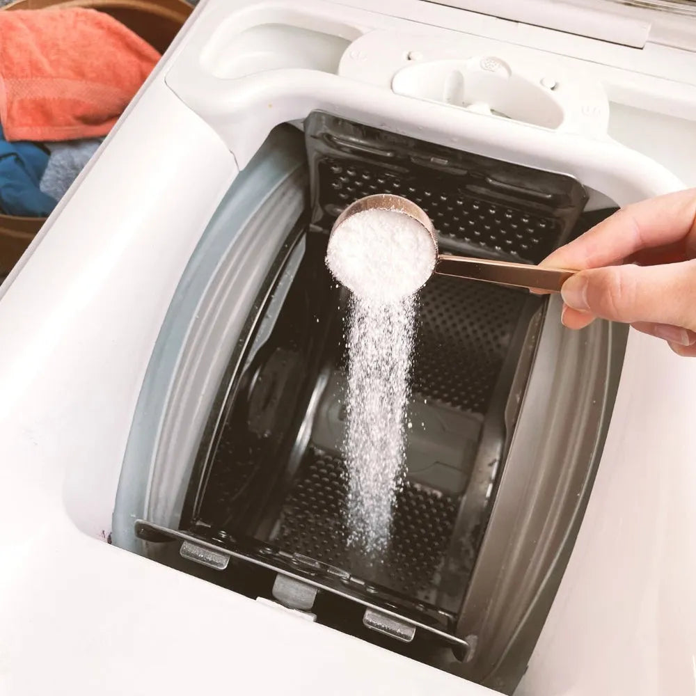 Utilisation pratique de la cuillère doseuse Pimpant pour verser la juste quantité de lessive écologique dans le tambour de la machine.