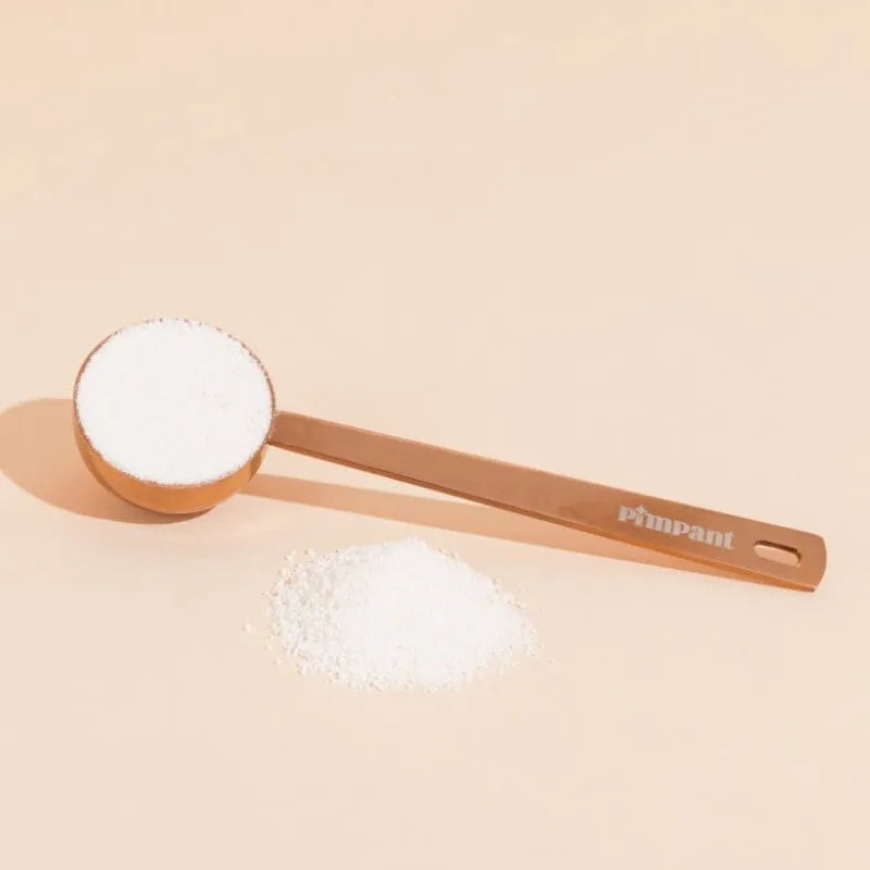 Gros plan sur la cuillère doseuse Pimpant remplie de lessive en poudre, l'alternative zéro déchet au gobelet doseur en plastique.