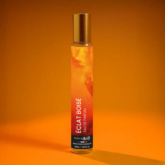 Flacon 30ml de l'Eau de Parfum Éclat Boisé par Born to Bio. Senteur hespéridée, boisée et aromatique sur un fond orange lumineux. Fabriqué en France.
