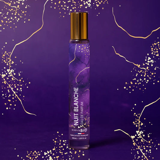 Eau de Parfum Nuit Blanche Born to Bio entourée d'étincelles dorées dans la nuit. Pyramide olfactive fascinante : Cassis, Cèdre et Fève Tonka.