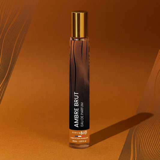 Eau de Parfum Ambre Brut Born to Bio entourée de motifs rappelant les ondes sonores ou les veines du bois. Pyramide olfactive puissante : Cardamome, Cèdre et Ambre gris.