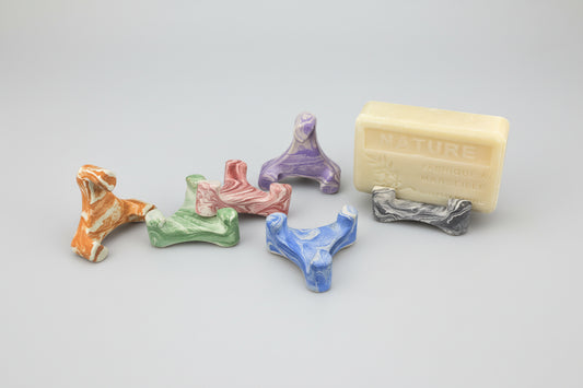 Assortiment de porte-savons minimalistes Trident en ciment marbré. Des accessoires artisanaux de différentes couleurs pour faire sécher vos savons naturels.